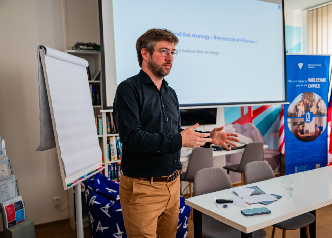 Baptiste Biancardini devant une présentation sur la stratégie Bienvenue en France